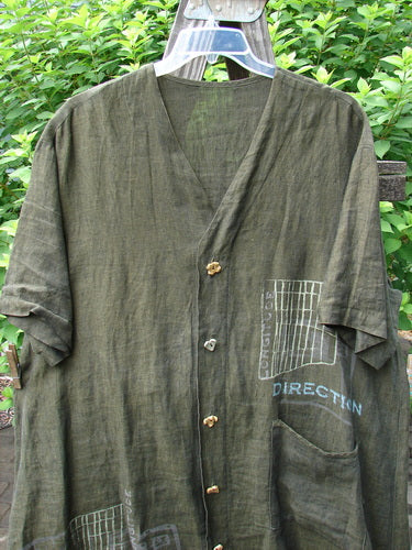 2000 Cross Dye Linen Downtown Jacket Directional Oregano Size 2: A green shirt on a swinger with a visor on a wood surface.