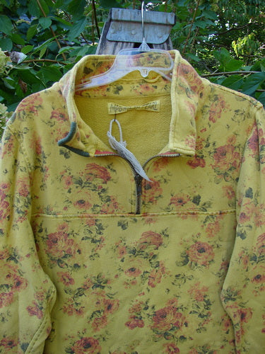 Magnolia Pearl NWT Cotton Fleece Asher Pullover Sweatshirt Vintage Rose Sunnies OSFA, featuring a rose-pattern, short zipper, and distinct raw edges, hanging on a clear hanger against lush greenery.