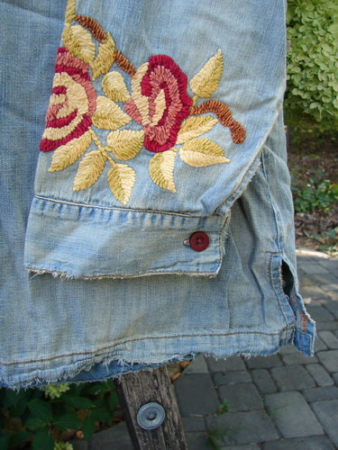 Magnolia Pearl NWT Embroidered Denim Isabel Shirt Washed Indigo OSFA features a light-blue denim with a fringed hem, red button, and striking red, yellow, and brown floral embroidery, capturing vintage-inspired individuality.