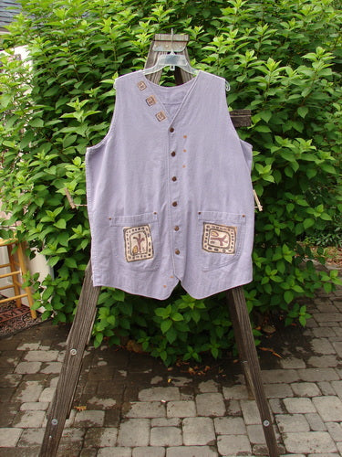 1996 Denim Visionary Vest Travel Stone Stratus Size 1: A light denim vest with metal buttons, rivet-topped pockets, and a rear buckle draw tab. Shirt tail front hem and upward scooped back line.