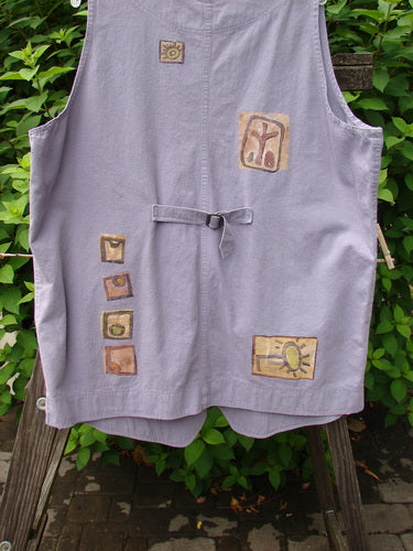 1996 Denim Visionary Vest Travel Stone Stratus Size 1: A light denim vest with V neckline, metal buttons, rivet-topped pockets, and a rear buckle draw tab. Shirt tail front hem with upward scooped back line. Features a Stepping Stone theme paint.