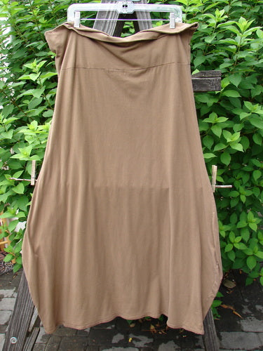 A brown dress on a clothes rack. Barclay Cotton Lycra Fold Over Bottom Bell Skirt in Coco, Size 2. Cross Over Front Banded Waistline, Lower Bell Accent, Pipped Lower Hem. Made from Organic Cotton and Lycra. Length: 40 Inches.
