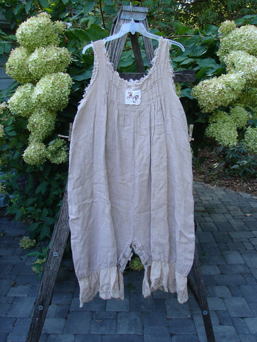 Magnolia Pearl Heavy Gauze Embroidered Signature Farm Love Overall Natural OSFA, featuring a scooped lace-trimmed neckline, wide gathered legs, and decorative patch, hanging from a wooden ladder outdoors.