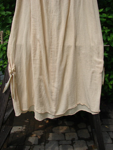 A white Barclay Gauze Tool Skirt, size 2, with a widening shape and gathered fall. Features a full drawcord waistline and vertical tabs accented in hand-dyed silk variegated ribbon. Unpainted for easy mixing and matching with other gauze pieces. Length is 40 inches.