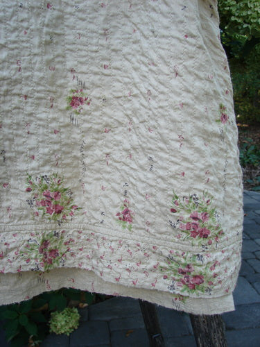 Magnolia Pearl European Cotton Quilted Hi Low Frances Top Vintage Rose OSFA draped outdoors, showcasing its cream fabric with pink rose sprays, wavy quilting stitches, and distinctive high-low hemline.