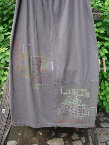2000 Block Skirt Directional Iron Size 2: A grey towel on a wooden board. Contrasting art with blended color changes. Patched and painted lower. Slightly flared shape. Directional theme paint and Blue Fish patch.