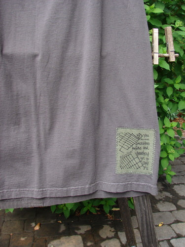 A grey cloth Block Skirt on a clothes rack, featuring a close-up of a piece of clothing with contrasting art and a painted lower. Size 2, made from organic cotton.