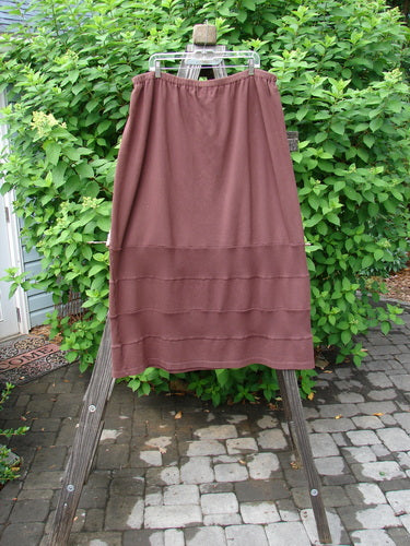 Barclay Interlock Rib Panel Skirt Unpainted Sepia Size 2: A skirt on a wooden stand, featuring continuous horizontal ribbed panels alternating with smooth cotton knitting and raised stitchery.