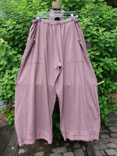 A pair of Barclay Batiste Bottom Double Flutter Pants in Dusty Rose, size 2, on a clothes rack. Made from medium weight organic cotton, these pants feature a replaced elastic waistband, double layer flutter batiste accents, and deep front entry pockets. Unpainted and in perfect condition.