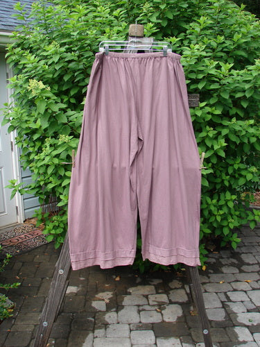 A pair of Barclay Batiste Bottom Double Flutter Pants in Dusty Rose, size 2, on a clothes rack. Made from medium weight organic cotton, these pants feature a full replaced elastic waistband, longer widening lowers with a double layer of flutter batiste, and deep front entry pockets. Unpainted and in perfect condition.