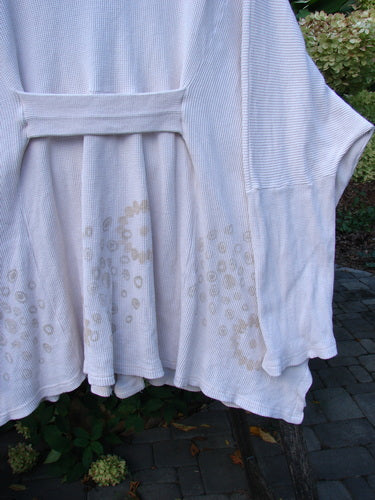 1997 Thermal Voyage Roadside Jacket Windy Floral Shell OSFA draped on a wooden chair, showcasing its waffle-knit texture, off-white tone, fabric belt, and faint tan circular pattern near the hem.