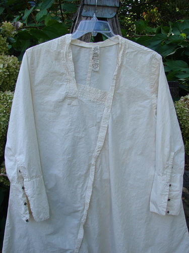 Magnolia Pearl Cotton Poplin Wabi Diagonal Tunic Natural OSFA displayed on a clear hanger, features a square neckline, buttoned cuffs, and unique diagonal seams, embodying the Bluefishfinder's vintage, expressive style.