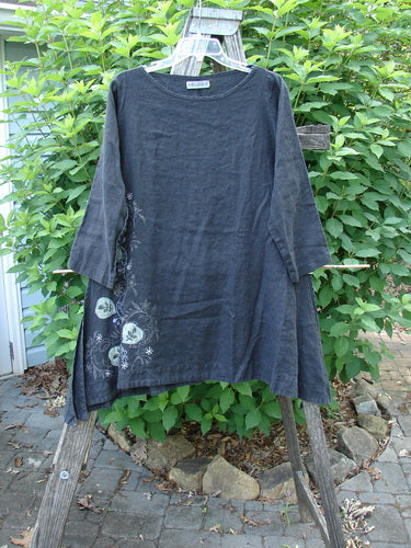 Barclay Linen Tall Vent Tunic Side Garden Black Size 1 features a flowy A-line shape with tall vented sides, a rounded neckline, and three-quarter length sleeves, displayed on a wooden rack.