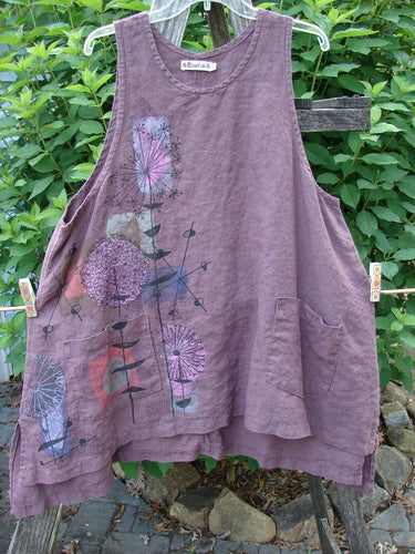 Barclay Linen Two Pocket Shirttail Pinafore Starburst Plum Wine Size 1, featuring a starburst pattern and double exterior pockets, displayed on a fence, highlighting its flowy A-line silhouette and rounded neckline.