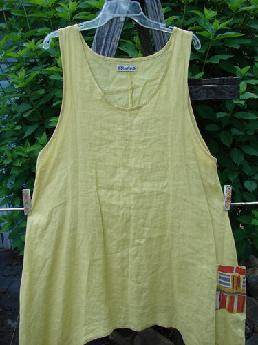 Barclay Linen Single Side Pocket Pinafore Geos Sunshine Size 1 hangs on a clothesline, showcasing its sweeping A-line flair, deeper scoop neckline, and painted exterior pocket.