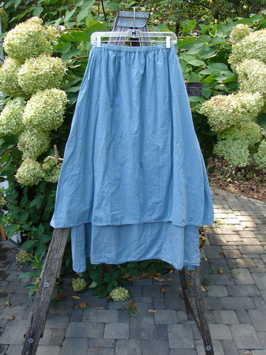 Barclay NWT Batiste Layer Skirt Unpainted Green Sea Size 0, featuring a two-tiered design with a full elastic waist, displayed on a hanger against a garden backdrop.
