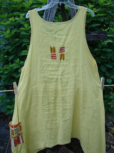Barclay Linen Single Side Pocket Pinafore Geos Sunshine Size 1, showcasing a sweeping A-line flair with a geometric-themed painted pocket, hanging on a clothesline, reflecting BlueFishFinder's creative vintage style.