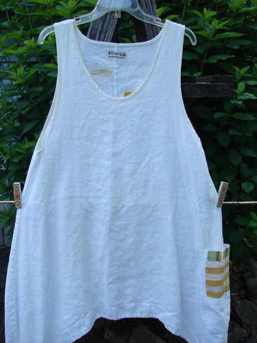 Barclay Linen Single Side Pocket Pinafore Geos White Size 1 displayed on a clothesline, showcasing its A-line flair, deeper scoop neckline, and unique exterior painted pocket in a geo theme.