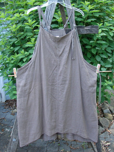 Close-up of the Barclay Linen Rayon Pucker Side Pocket Apron Jumper in Unpainted Bark, featuring double front rounded pockets, adjustable shoulder straps, and a softly textured vertical pucker rib.