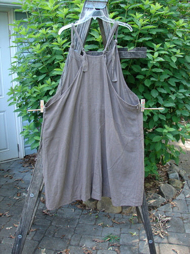 Barclay Linen Rayon Pucker Side Pocket Apron Jumper Unpainted Bark Size 1 displayed on a wooden ladder, highlighting its softly textured vertical pucker rib and adjustable shoulder straps.