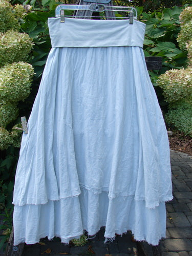 Barclay NWT Batiste Fold Over Raglan Silhouette Skirt Unpainted Dew Size 1, showcasing a pale-blue, maxi-style design with a wide waistband and two generously tiered layers, elegantly displayed outdoors.