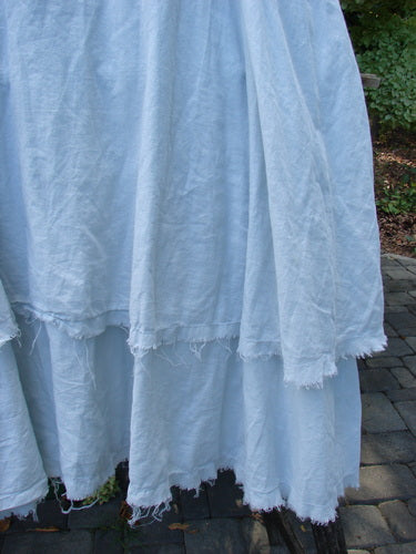 Barclay NWT Batiste Fold Over Raglan Silhouette Skirt Unpainted Dew Size 1, featuring a loose, off-white, double-layered cotton with frayed edges, draped over cobblestones, showcasing its generous, tiered design.