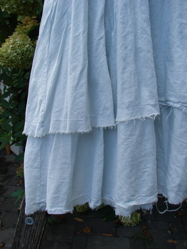 Barclay NWT Batiste Fold Over Raglan Silhouette Skirt Unpainted Dew Size 1 features a tiered, frayed hem design, showcasing its A-line flair and generous two-tiered presentation, hanging outdoors.