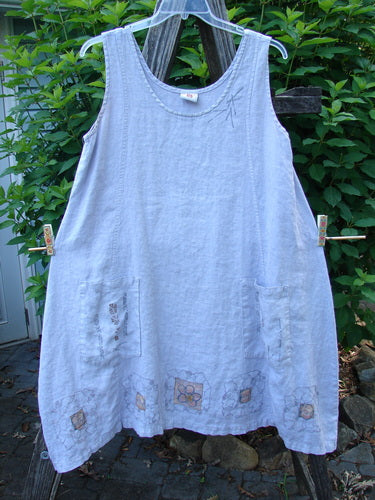 Barclay Linen Pocket Pinafore Mosaic Floral Lavender Size 0 on a clothesline, showcasing scoop neckline, A-line flair, and double exterior pockets with mosaic floral design, made from lightweight linen for summer collection.