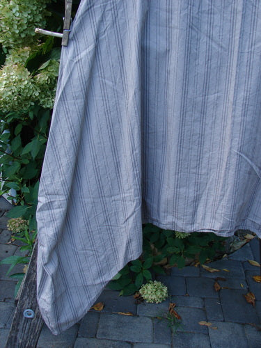 Barclay NWT Percale Hado Shift Stripe Moon Rock Sand Size 1 draped over a wooden rail, showcasing its deeper scoop neckline and widening A-line shape with vertical pinstripes against a natural outdoor backdrop.