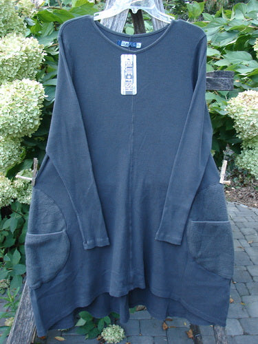 Barclay NWT Thermal Cloud Forest Pocket Tunic Unpainted Smoke Size 0 displayed outdoors, showcasing its long sleeves, rounded neckline, A-line flare, and distinctive patch pockets, suspended on a clear hanger.
