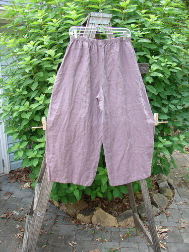 Barclay Linen Every Day Curve Pant Unpainted Dusty Plum Size 1 displayed outdoors on a wooden rack, showcasing its billowing fall, curved panels, and elastic waist, emphasizing versatile, vintage-inspired style.