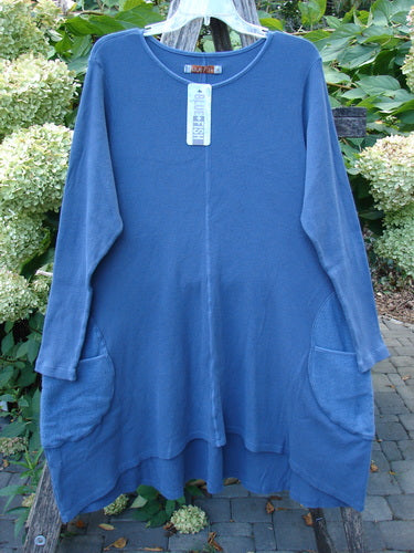 Barclay NWT Thermal Cloud Forest Pocket Tunic Top in Unpainted Vintage Indigo, size 1, hangs on a bench, showcasing its rounded neckline, long sleeves, A-line flare, and scooped hemline.