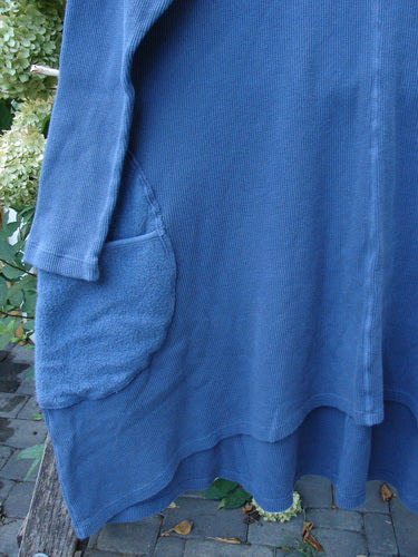 Barclay NWT Thermal Cloud Forest Pocket Tunic Top in Vintage Indigo features a rounded fleece-like side pocket, hanging outdoors against stone pavers with greenery, showcasing its cozy, A-line design.