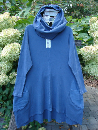 Barclay NWT Thermal Cloud Forest Pocket Tunic Top in Vintage Indigo hangs outdoors, featuring a draped cowl neck, long sleeves, large patch pockets, and a graceful flared hemline.