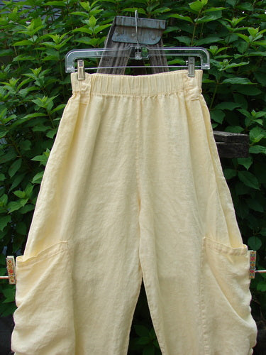 Barclay Linen Tie Bottom Pocket Bloomer Buttercup Size 1 displayed on a clothes rack, showcasing its full elastic waist, front exterior drop pockets, widening bloomers with pull ties, and belt loops for versatile styling.