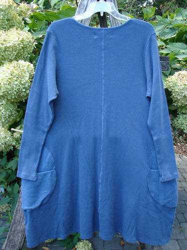 Barclay NWT Thermal Cloud Forest Pocket Tunic Top in Vintage Indigo, displayed on a hanger outdoors, showcases an A-line silhouette with long sleeves and large rounded pockets near the hips.
