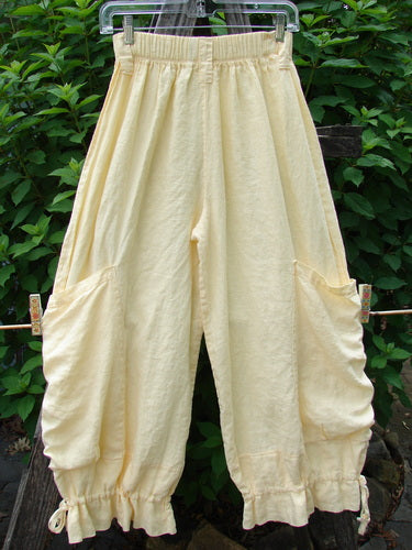 Barclay Linen Tie Bottom Pocket Bloomer Buttercup Size 1 displayed on a clothesline, showcasing its elastic waist, exterior drop pockets, blooming lowers with pull ties, and slightly cropped length.
