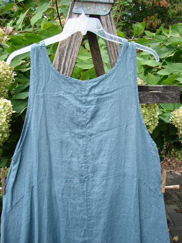 Barclay NWT Linen Tulip Midlayer Overpiece Unpainted La Mer Size 0, displayed on a clear hanger over a wooden ladder, showcasing its loose fit, scoop neckline, and tiered empire waist design.