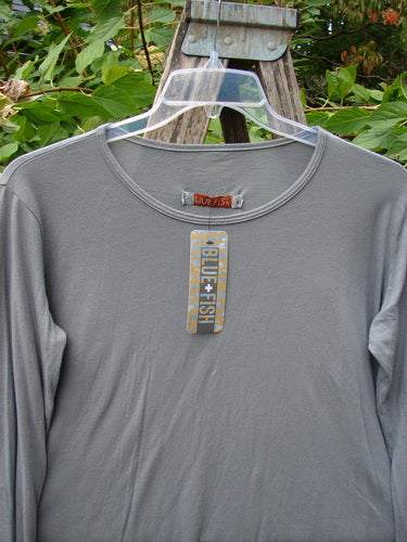 Barclay NWT Batiste Long Sleeved Layering Tee Unpainted Moonlight Size 1, featuring long narrowing sleeves and raw cut rolled edges, displayed on an outdoor wooden step-ladder with a Blue Fish swing-tag visible.
