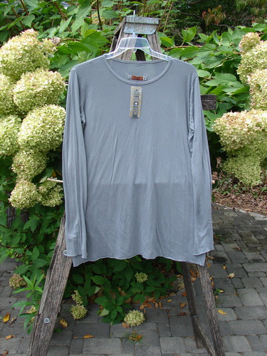The Barclay NWT Batiste Long Sleeved Layering Tee Unpainted Moonlight Size 1 drapes elegantly on a ladder, showcasing its long narrowing sleeves, raw cut rolled edges, and rounded neckline.