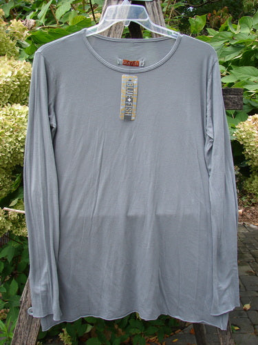 Barclay NWT Batiste Long Sleeved Layering Tee Unpainted Moonlight Size 1, featuring long narrowing sleeves, raw cut rolled edges, and a rounded neckline, displayed on a hanger amidst lush greenery.