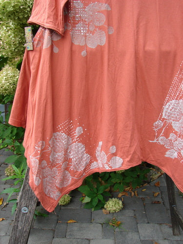 Barclay NWT Origami Tunic Top Berrie Patch Orange Cachi Size 0, displayed on a wooden ladder, showcasing its unique floral and dot pattern, open sides, and raw flutter edgings against outdoor greenery.