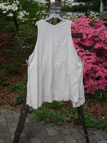 Vintage Barclay Slub High Vent Figure 8 Lace Pocket Pinafore Dress on a clothes rack outdoors. Unique curvy seams, art panel, wrap pockets, A-line shape, high side vents. Unpainted, lacy accents. Size 2.