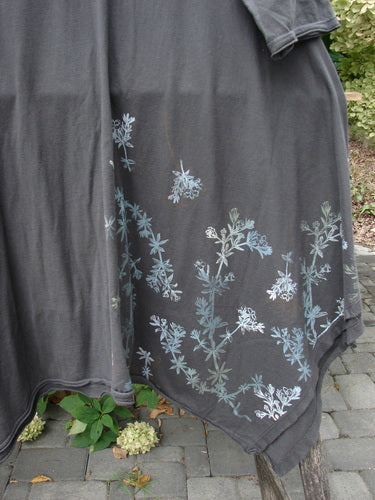 Barclay NWT Origami Tunic Top Floral Branch Black Sand Size 0 drapes outdoors, featuring an asymmetrical hem with pale blue and white botanical print, raw flutter edges, and open sides.