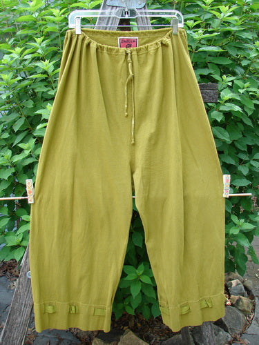 Barclay Bow Bottom Pantaloon Unpainted Green Olive Size 0 displayed on a fence, showcasing its full elastic waistline, textured ribbon bows, and buttonholes at the cuffs, embodying vintage Blue Fish creativity.