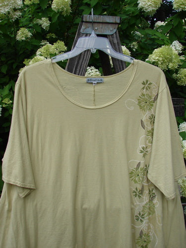 Image alt text: Barclay High Low Top Dandelion Trail Dawn Size 2: A swingy shirt on a wooden stand, featuring a deeper rounded neckline and a varying upward front hemline. Made from organic cotton.