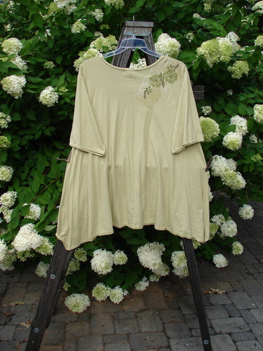 Image alt text: Barclay High Low Top Dandelion Trail Dawn Size 2: A swingy shirt with white flowers on a wooden swinger.