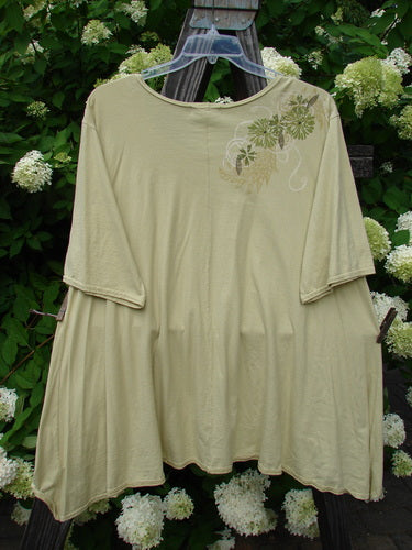 Image alt text: Barclay High Low Top Dandelion Trail Dawn Size 2: Swingy shirt on a wooden post, featuring a deeper rounded neckline and varying upward front hemline. Organic cotton fabric.