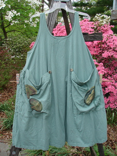 Vintage 1998 Harvest Pinafore Organic Garden Kale Size 1, featuring oversized painted pockets, drawcord gathers, and a unique veggie theme. A green apron with pockets on a clothesline, embodying creative freedom and individuality.