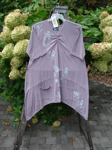 Barclay NWT Perfect Day Pocket Tunic Dress Love Dove Sea Fog Size 0 displayed on a wooden hanger, showcasing its asymmetrical handkerchief hem, floral prints, gathered neckline, and exterior pockets.